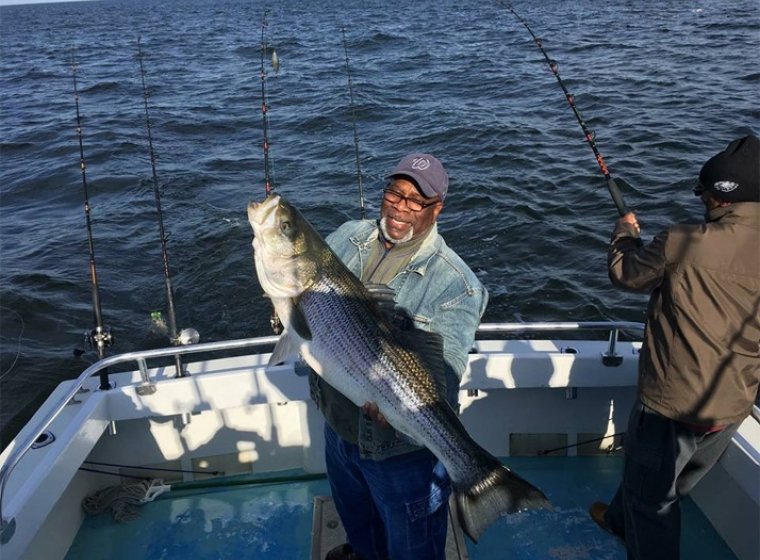man holding large fish on boat 