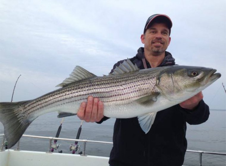 man holding large fish on boat dock